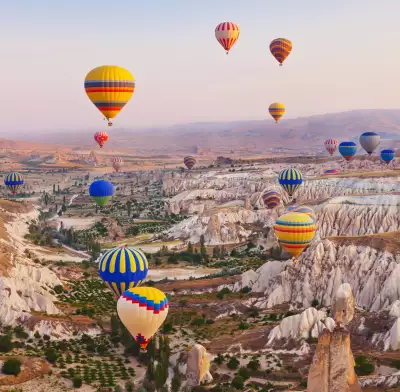 Bucket list ideas for travellers | Hot air balloons flying over the rocky landscape in Cappadocia, Turkey