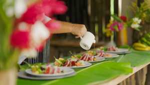 Liamuiga Natural Farms | A hand pours sauce on top of a row of plates at Liamuiga Natural Farms