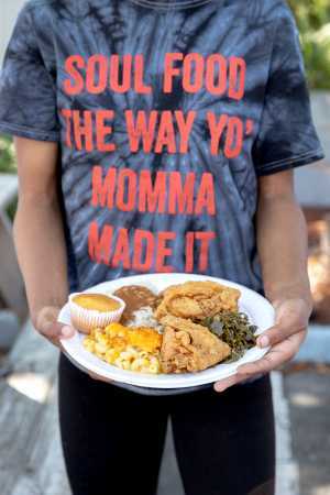 Myrtle Beach | A hand holds a plate of chicken, mac and cheese, collard greens and cornbread at Big Mike's Soul Food in Myrtle Beach
