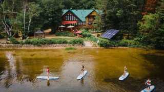 Ontario wellness retreats | A group of women paddle boarding on a lake at Northern Edge Algonquin wellness retreat
