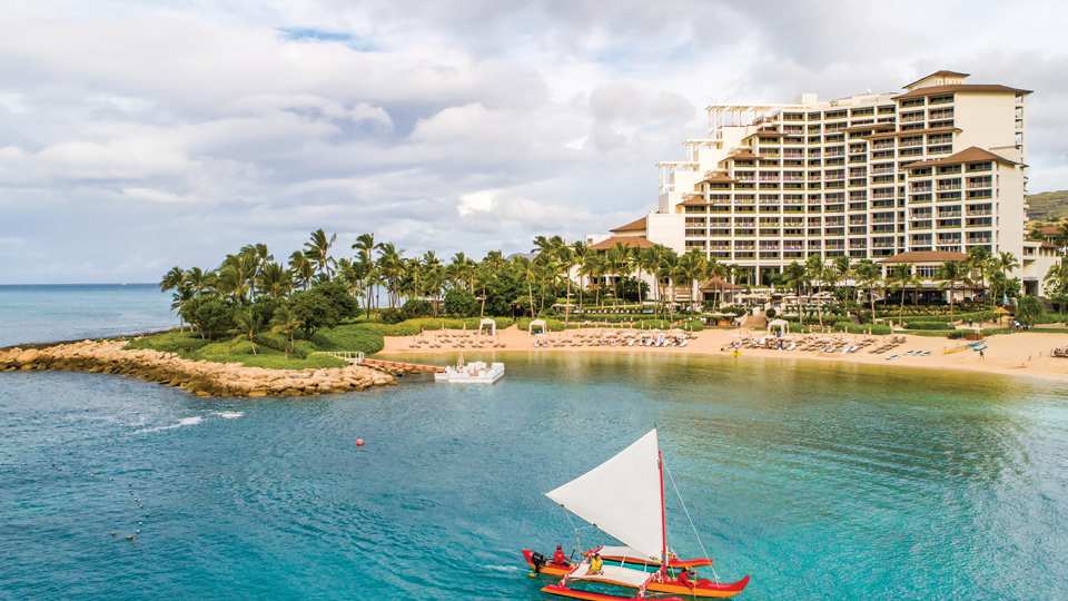 A Hawaiian canoe sails off the shore of the Four Seasons Resort Oahu