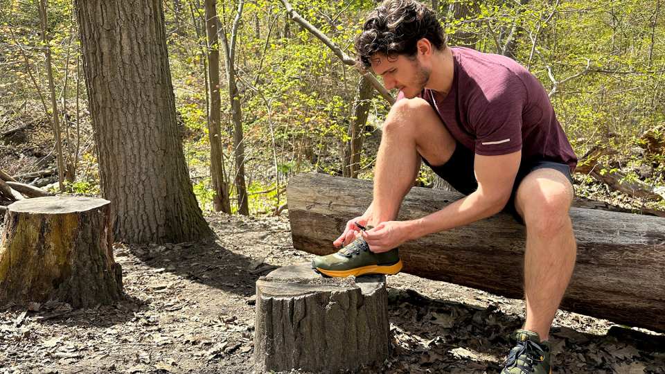 Columbia hiking shoes | Hunter Gutman sits on a log in the forest tying his hiking shoes