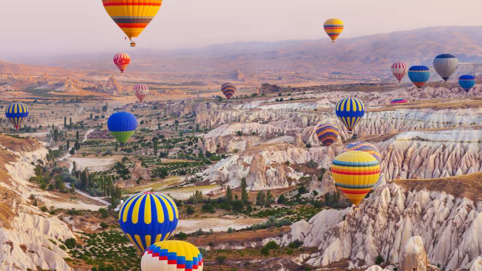 Bucket list ideas for travellers | Hot air balloons flying over the rocky landscape in Cappadocia, Turkey