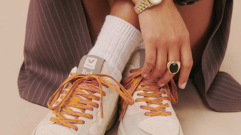 Veja X Reformation Sneakers | A woman is seated wearing a watch and sneakers