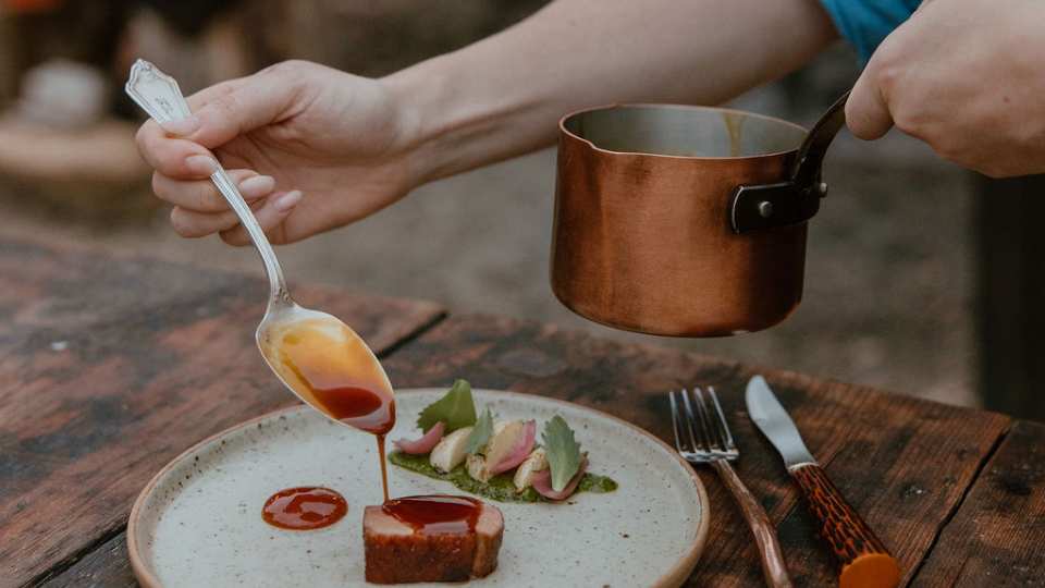 Grey County | A hand drizzles sauce over steak at Down Home in Grey County
