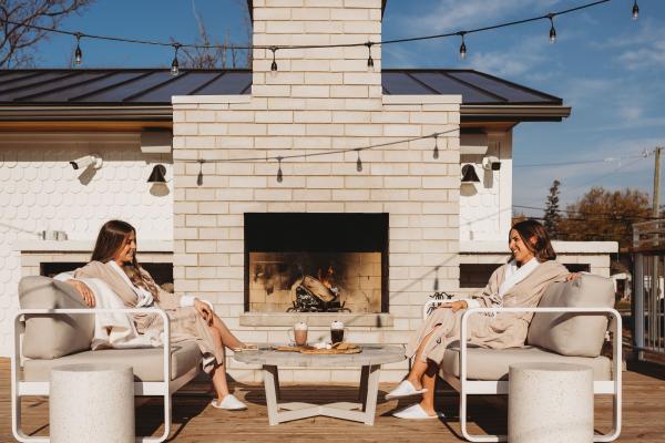 Wellness and travel gift ideas | Two women sit by the outdoor fireplace at The Beach Motel