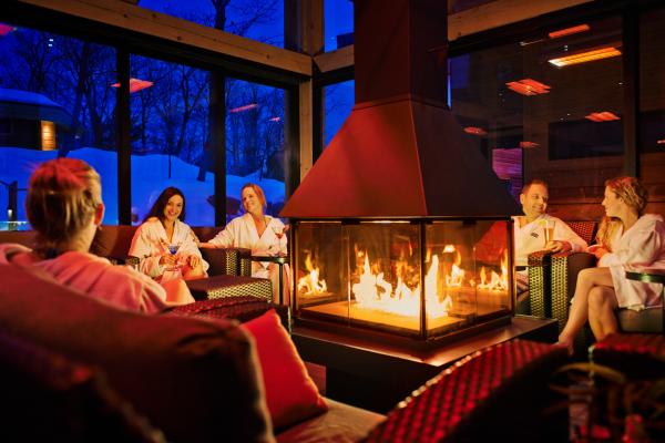 Nordik Spa-Nature - Chelsea, Quebec | People sit around the fire in the Panorama Lounge at Nordik Spa-Nature - Chelsea