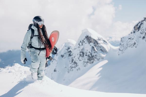A snowboarder walking on a mountain wearing the Men's Burton [ak] Swash GORE‑TEX 2L snowboarding jacket