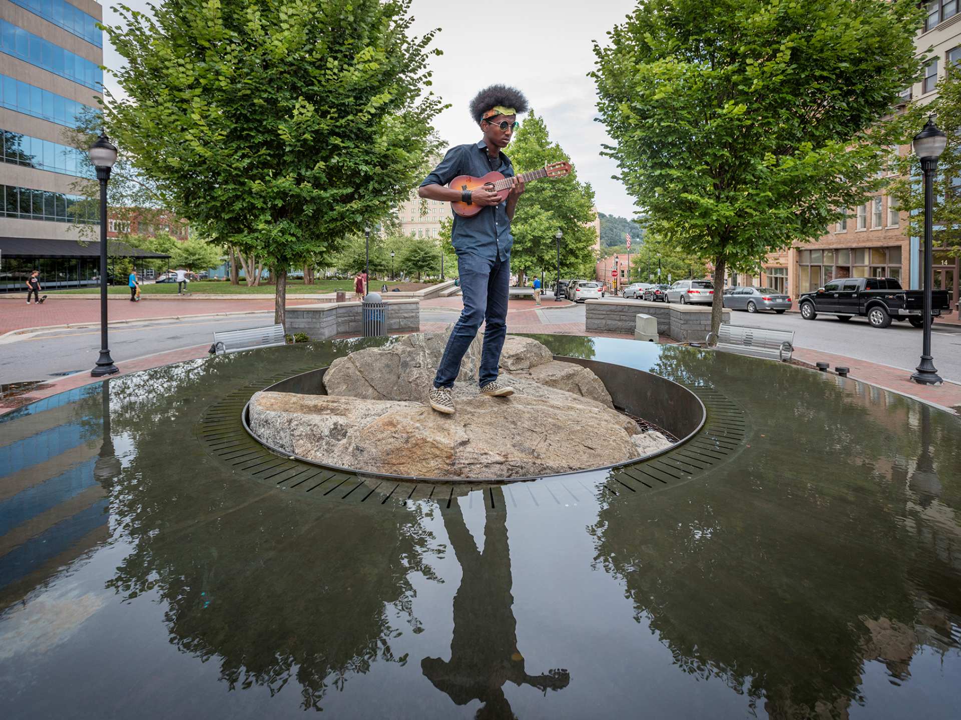 North Carolina | A street performer standing on rocks by water in downtown Asheville, North Carolina