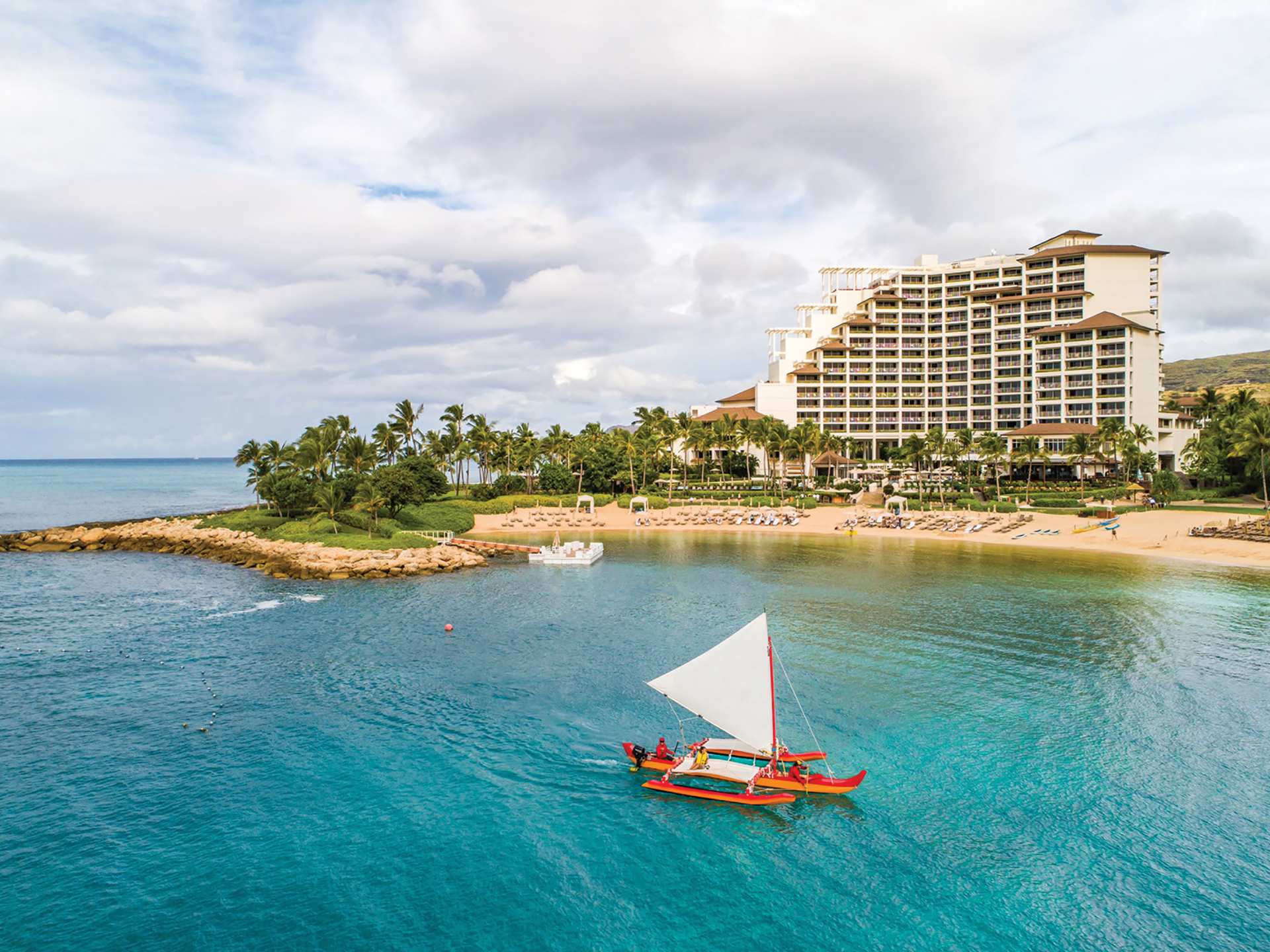 A Hawaiian canoe sails off the shore of the Four Seasons Resort Oahu