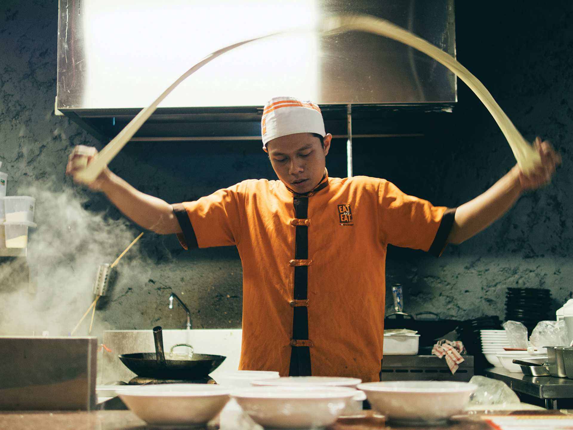 Mississauga | A man swinging a long strand of dough over his head