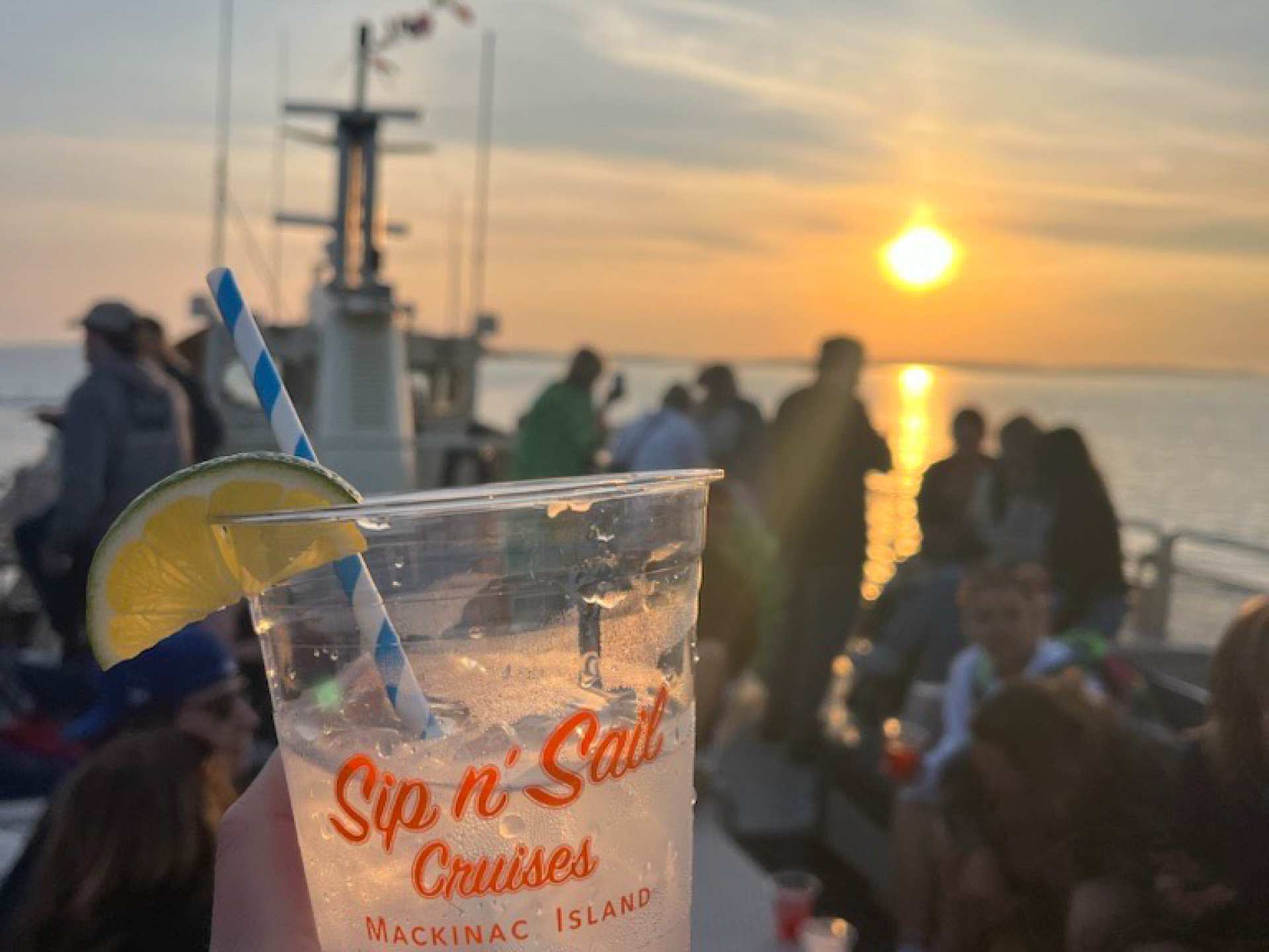 Mission Point | A person holding a drink on a boat looking out at the sunset on Mackinac Island