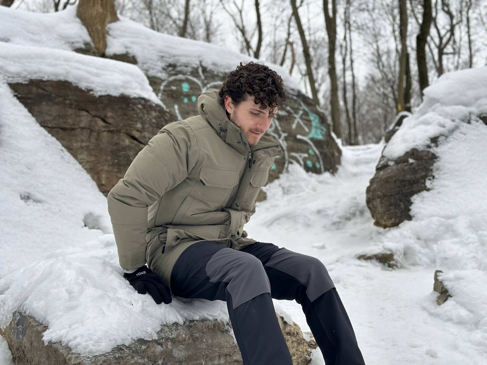 Escapism's Hunter Gutman sitting on a snowy rock in the Columbia Landroamer Collection