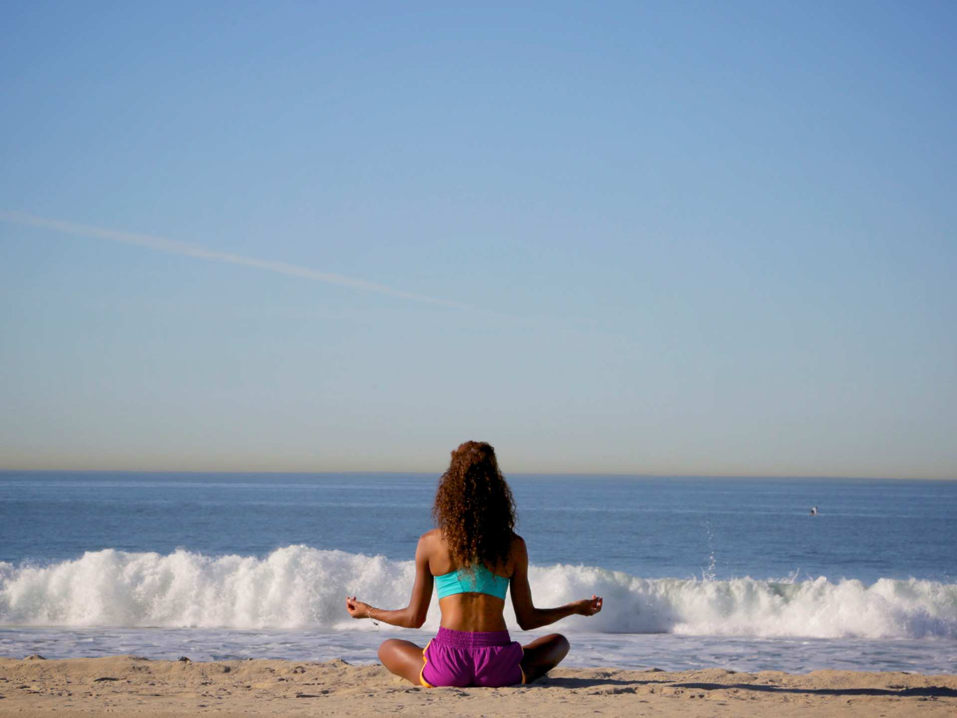 A person practicing yoga and meditation at Santa Monica beach