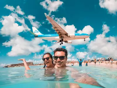 Saint Martin | A plane flies low over a couple on Maho Beach