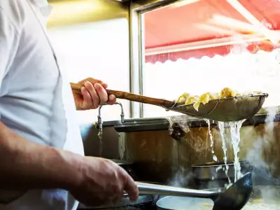 Culinary Adventure Co. | A chef stirring a dish in a strainer