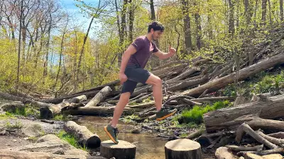 Columbia shoes | A man mid-jump between two logs in the forest