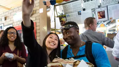 Kimpton Saint George | Two people on a food tour taking a selfie, holding a tray full of sandwiches