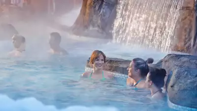 Nordik Spa Village - Chelsea, Quebec | People in an outdoor pool with a waterfall at Nordik Spa Village - Chelsea
