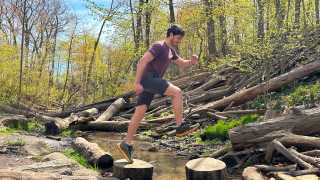 Columbia shoes | A man mid-jump between two logs in the forest