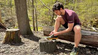 Columbia hiking shoes | Hunter Gutman sits on a log in the forest tying his hiking shoes