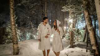Quebec Spa | A couple walking through the snowy forest at Scandinave Spa Mont-Tremblant