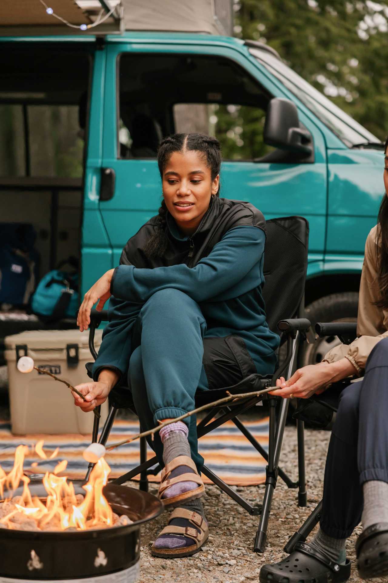 Roasting marshmallows by the fire in the Smash + Tess X MEC Fresh Air Fleece Jumpsuit