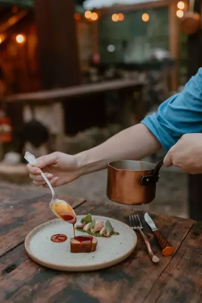 Grey County | A hand drizzles sauce over a steak dish at Down Home in Grey County