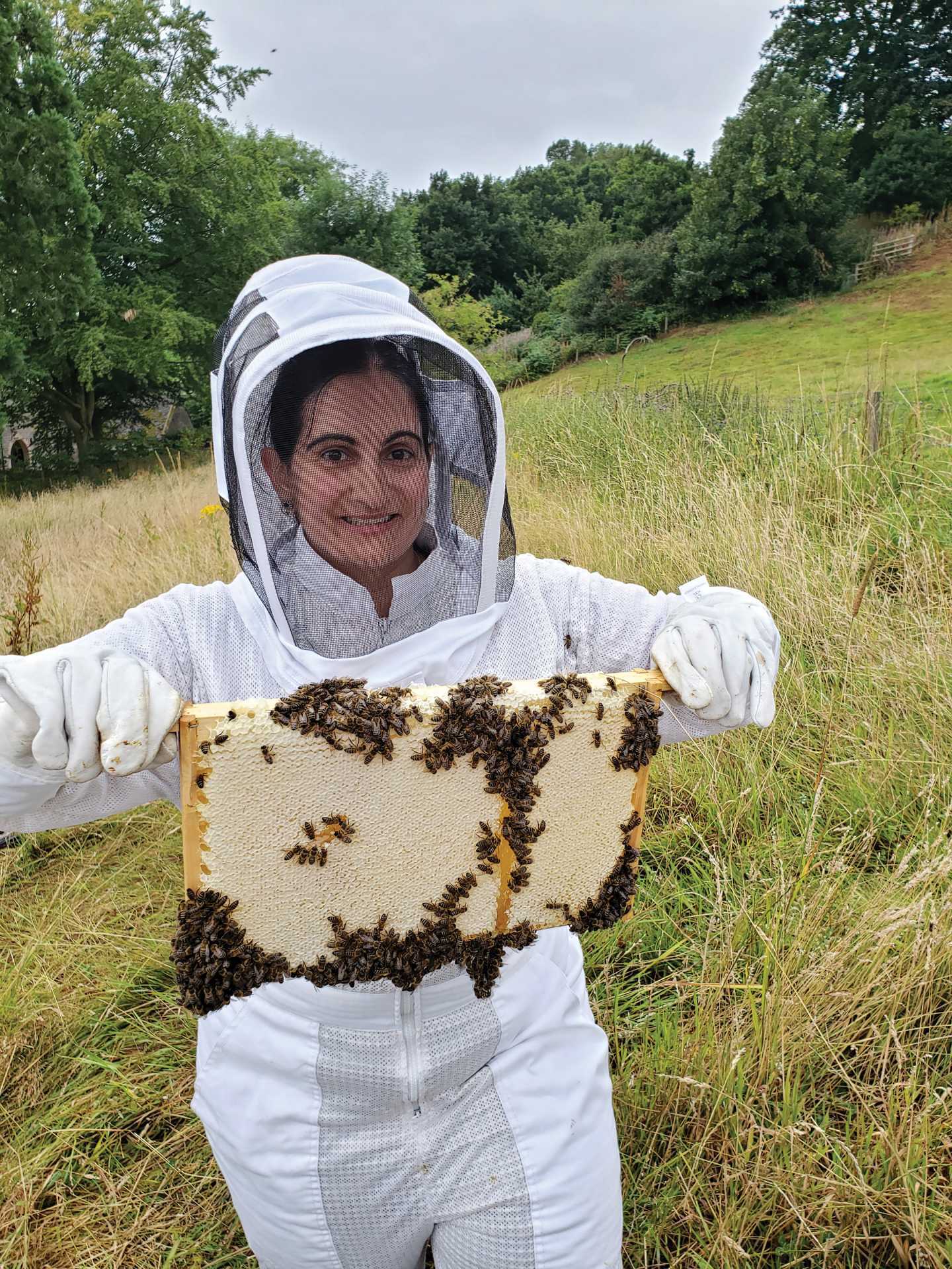 Sabrina Pirillo gingerly holds up a beehive