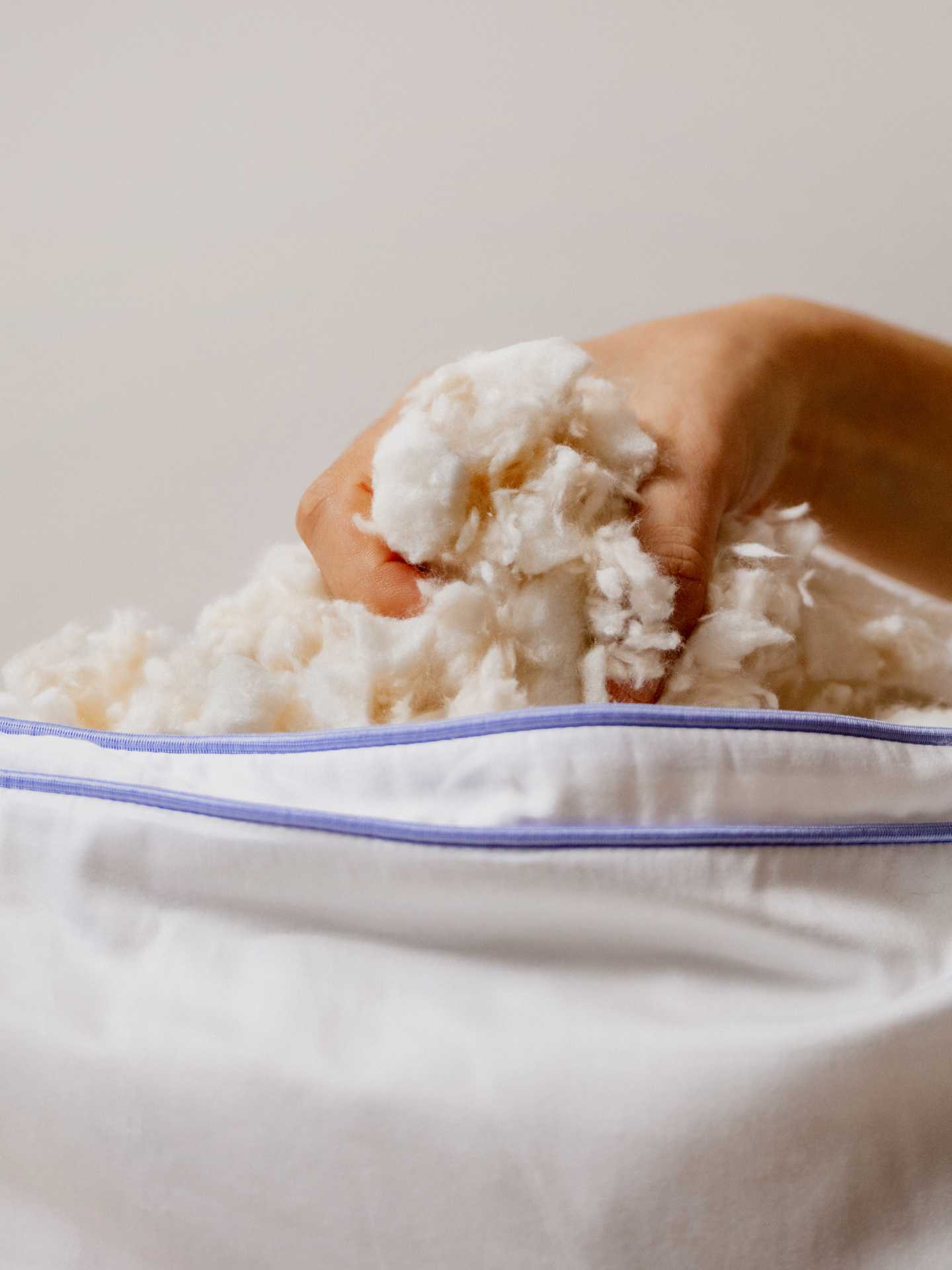 A hand removing the stuffing from The Henrie Adjustable Pillow