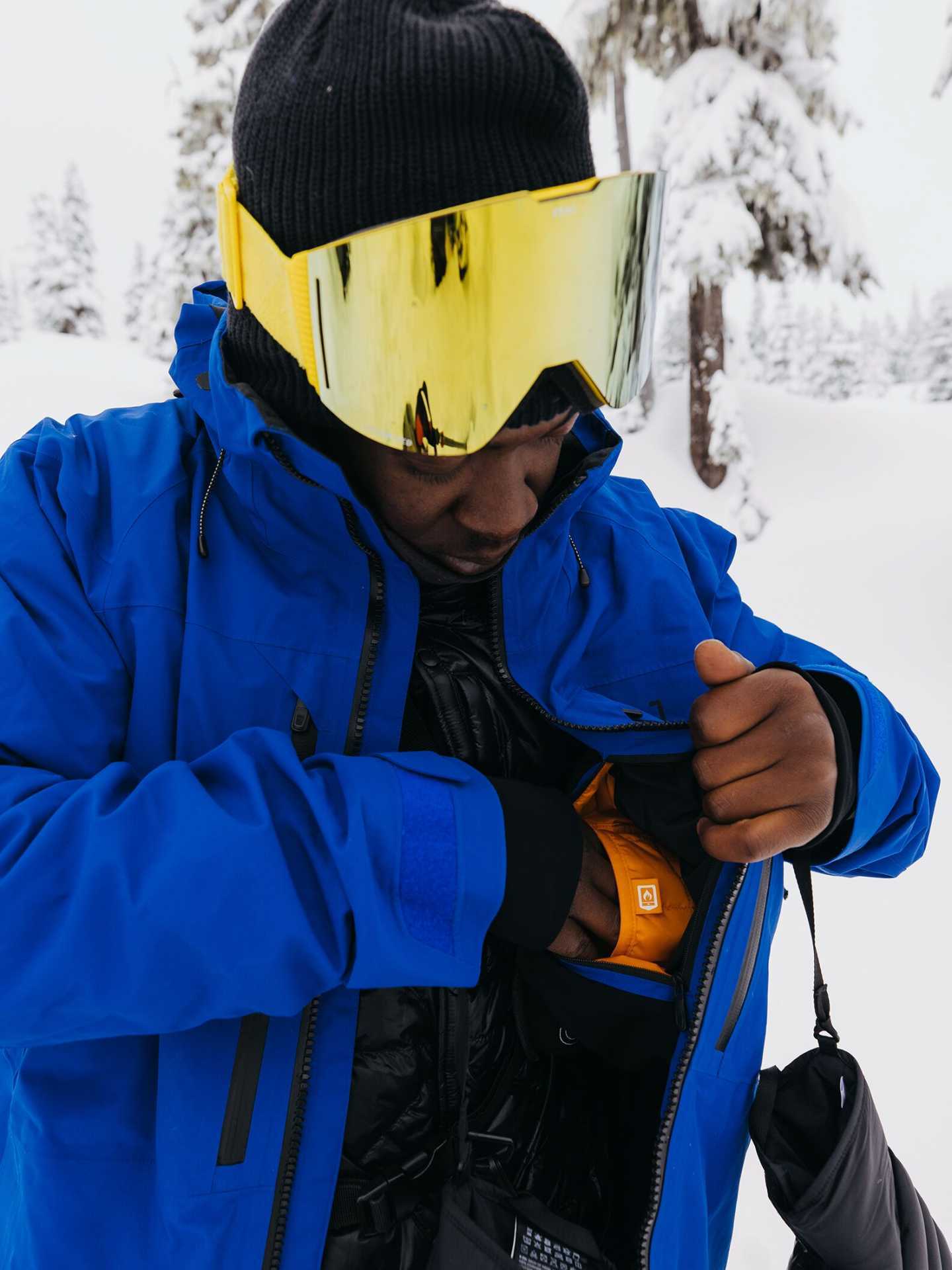 A snowboarder using the inner pocket of the Men's Burton [ak] Swash GORE‑TEX 2L snowboarding jacket