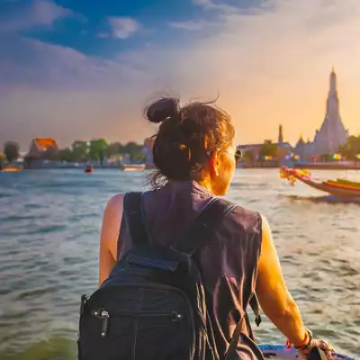 Woman sitting near the water with a city in the distance