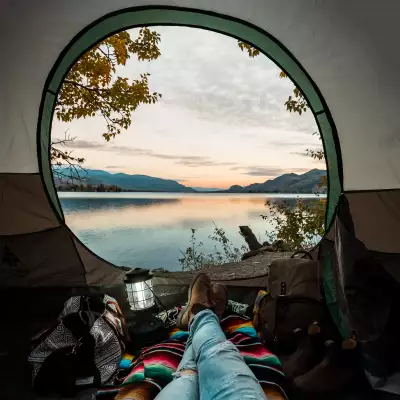 A person sitting in their tent looking out at the water in Osoyoos, B.C.