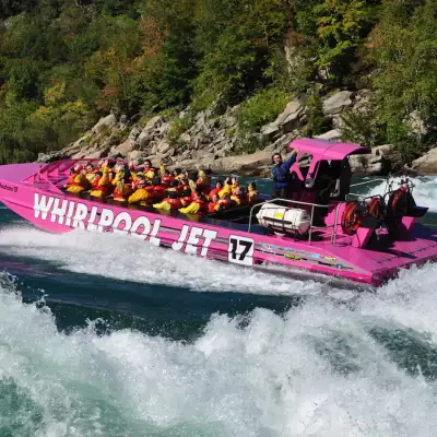 A group of people on the Niagara River in a pink jet tours boat