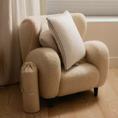 The Henrie Adjustable Pillow on a fluffy chair
