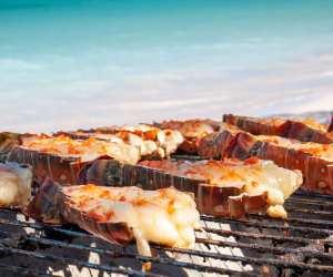 Treasure Beach Food, Rum & Reggae Festival in Jamaica | Lobsters cooking on the grill against a beach backdrop