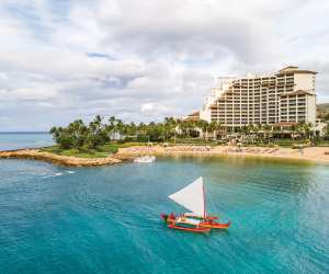 A Hawaiian canoe sails off the shore of the Four Seasons Resort Oahu