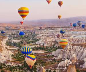 Bucket list ideas for travellers | Hot air balloons flying over the rocky landscape in Cappadocia, Turkey