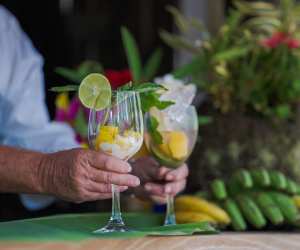 Liamuiga Natural Farms | A man's hand serves two glasses filled with mango, lime and ice at Liamuiga Natural Farms