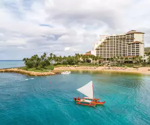 A Hawaiian canoe sails off the shore of the Four Seasons Resort Oahu