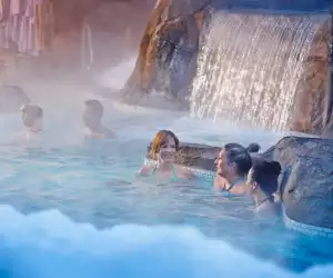 Nordik Spa Village - Chelsea, Quebec | People in an outdoor pool with a waterfall at Nordik Spa Village - Chelsea