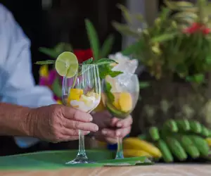 Liamuiga Natural Farms | A man's hand serves two glasses filled with mango, lime and ice at Liamuiga Natural Farms