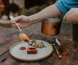 Grey County | A hand drizzles sauce over steak at Down Home in Grey County